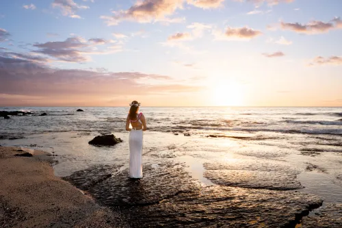 Bride walking on reflective wet sand during magical golden hour sunset in Hawaii