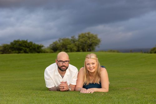 Happy couple lying together on lush green golf course for Hawaii wedding photos