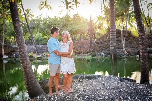 Couple standing in tropical garden path with palm trees during golden hour in Hawaii