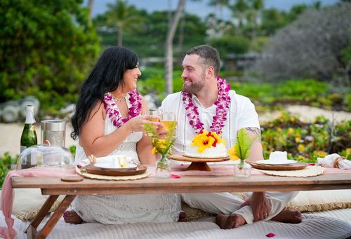 Beach wedding with pink plumeria leis and tropical food spread in Hawaii